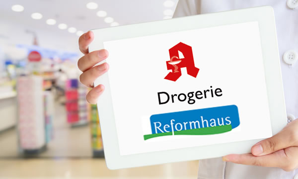 Mann hält ein Schild mit einem Apothekenlogo sowie dem Schriftzug Reformhaus